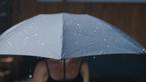 Woman Sheltering Under Umbrella During Rain Shower