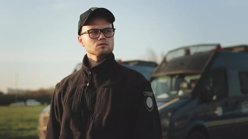 Young Man in Uniform Standing Outdoors near Vehicles