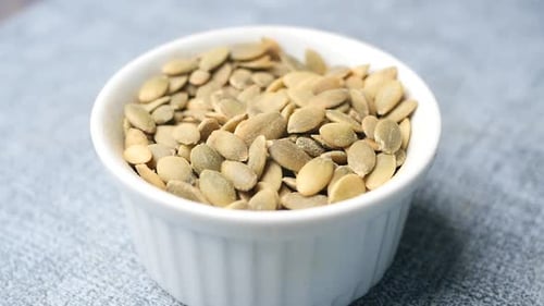 Pumpkin Seeds in a Small Bowl on Black Background