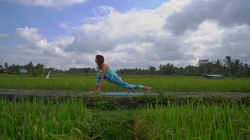 Slowmotion Steadicam Shot of a Young Woman Practicing Yoga on a Beautiful Rice Field