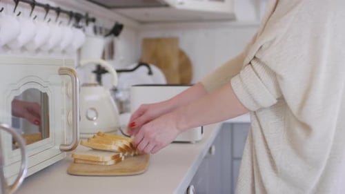 Woman Toasting Bread in a Bright White Kitchen