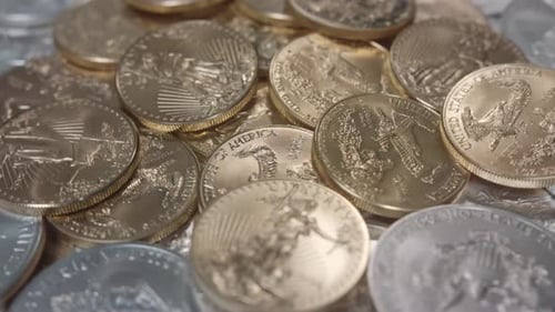 American Gold Eagles-Münzen auf einem Stapel Silbermünzen, die sich nach links drehen