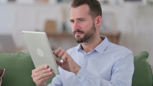Frustrated Man Cries While Using Tablet at Home