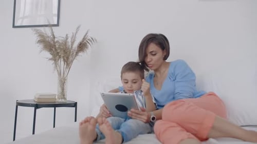 Mother and Child Play on Tablet in Bedroom