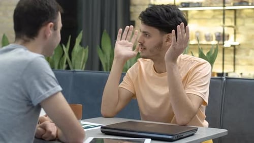 Portrait of Excited Young Man Talking with Friend in Cafe
