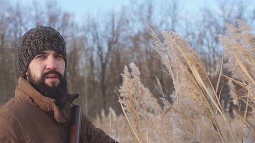 Bearded Man Aims Rifle in Winter Forest