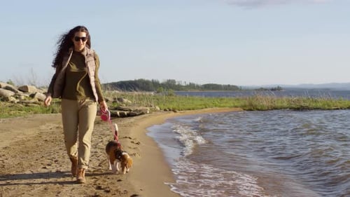 Young Woman Enjoying Walk with Dog along Lake Shoreline