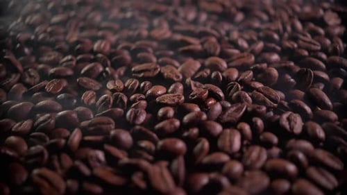 Ароматные кофейные зерна в процессе обжарки с присутствием небольшого количества дыма