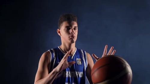 Young African American Guy in the Uniform of a Basketball Player Poses in the Studio on a Black