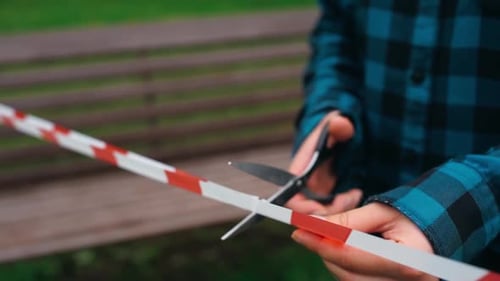 Cutting the Cordon Tape Ribbon with Scissors. End of Mobility Restrictions Coronavirus. Scissors