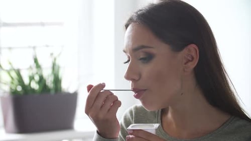 Woman Eating Yogurt for Healthy Breakfast Snack Indoors