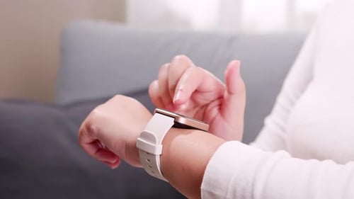 Close up shot of a woman hand who touch and scrolling on a smartwatch in order to quickly check appl