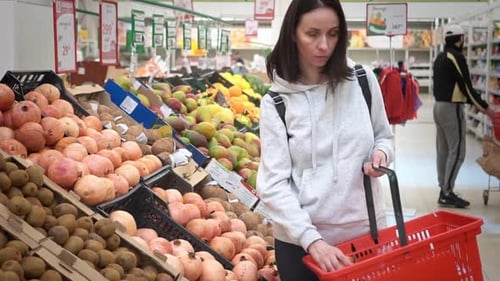 Midrange Caucasian Woman in a White Sweater in a Shopping Mall with Fruits in a Supermarket Buys a