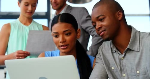 Team Collaboration Around Laptop in Modern Office