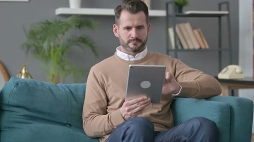 Adult Man Using Tablet While Seated on Couch