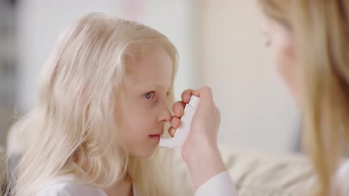Mère donnant un inhalateur à sa fille souffrant d'une crise d'asthme