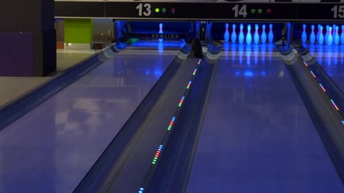 Bowling-Spiel. Eine Bowlingkugel fährt die Gasse entlang und schlägt Stifte um