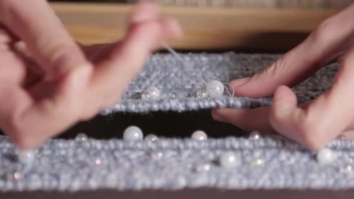 Hands Sewing Pearls and Beads on Fabric