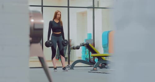 Woman Doing Lunges with Dumbbells at the Gym
