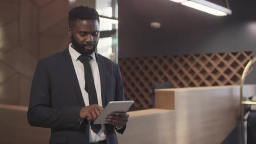 Businessman with Tablet Standing in Hotel Lobby