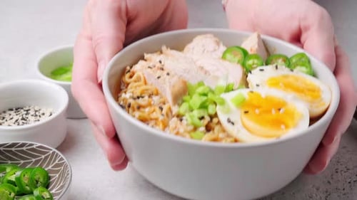 Person Places Bowl of Ramen on Counter