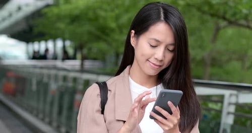 Woman Types on Smartphone Outdoors in Urban Park
