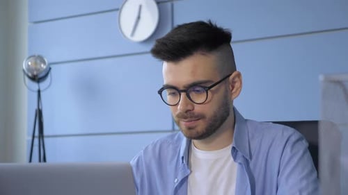 Young Adult Working on Laptop in Modern Office