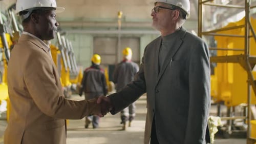 Two Engineers Shaking Hands and Speaking in Factory