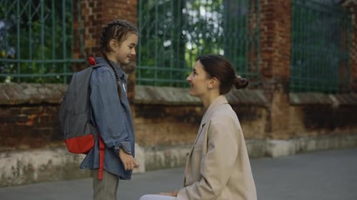 Loving Mother Hugs Daughter Outside Building