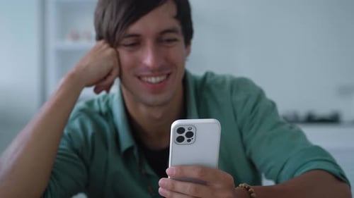 Young Man Smiling Using Mobile Phone Indoors