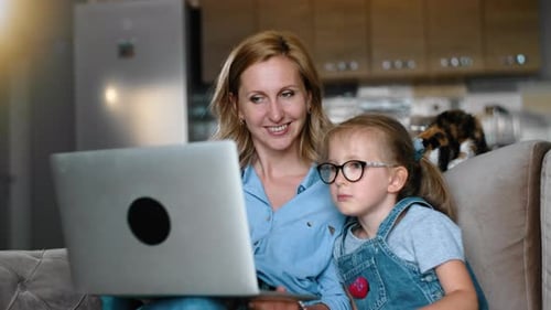 Woman and Child Use Laptop Computer on Couch
