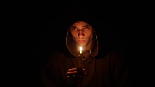 Man Dark Cloak Stands Dark with Hood His Head Looks Into Camera While Holding