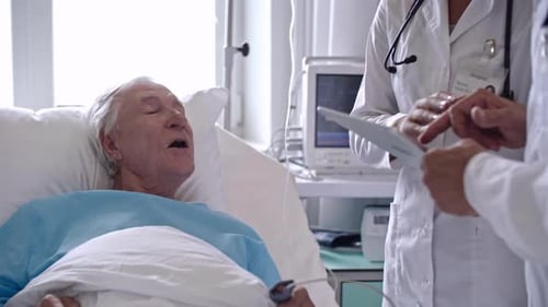 Doctors Reviewing Data with Patient in Hospital