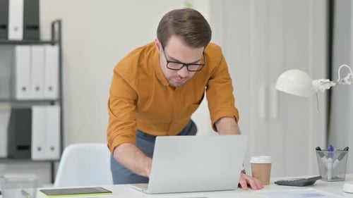 Young Man Standing Working on Laptop in Office