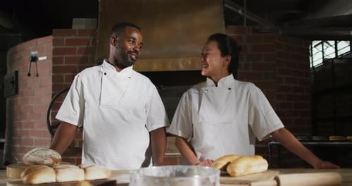 Animation of two diverse male and female bakers smiling at camera in bakery