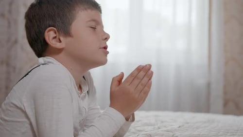 Boy Lying on Bed Saying Prayer