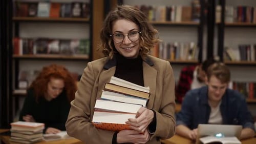 Portrait of Attractive European Girl Student Holding Books in High School Library Smiling Looking at