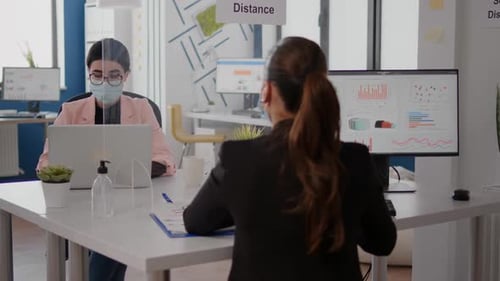 Un pigiste discute avec un collègue de la stratégie d'entreprise tout en étant assis dans un nouveau bureau normal