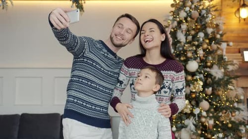 Family Taking Christmas Selfie in Front of Tree