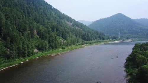 Drone Flies Over River in Mountainous Countryside.