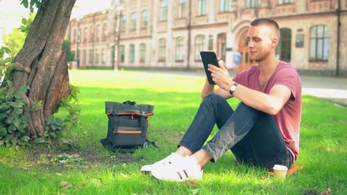 Man Using Tablet on College Campus Lawn
