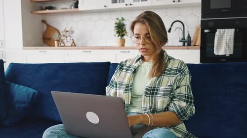 Close Up Shot of Young Blonde Lady Wearing Glasses Typing on Laptop Computer Making Online Research