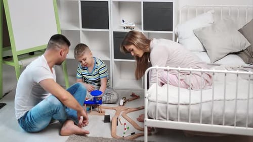 Enthusiastic Family Mother Father and Son Playing Toy Car Road Together at Comfortable Bedroom