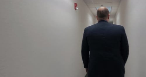 Man in corporate office environment walking through hallway