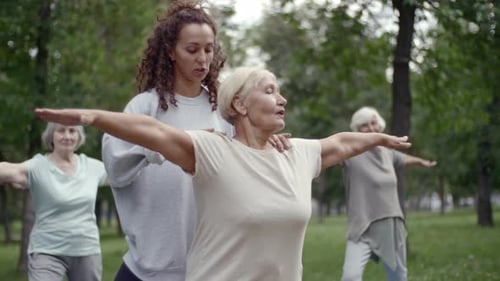 Yoga Instructor Helping Seniors in a Grassy Park