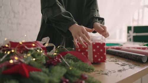 Hands Tying Bow on Christmas Present