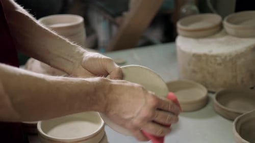 Man Hands Makes Clay Plates in Pottery Workshop Top Close Up View Focus on Stained Hand