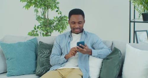 Man Relaxing on Couch Using Mobile Phone