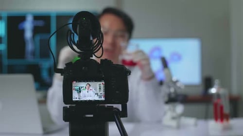 Camera Display Of Asian Scientist Researching In The Laboratory With Test Tube And Speaking