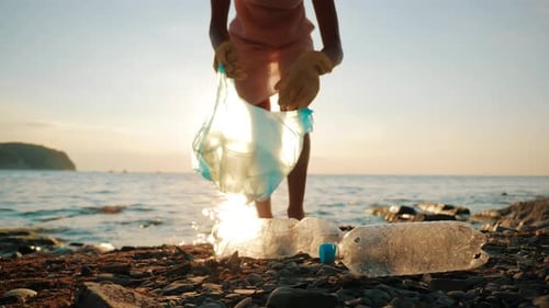 Volunteer Girl Collects Trash in the Trash Bag. Plastic Bottles and Other Trash on Sea Beach